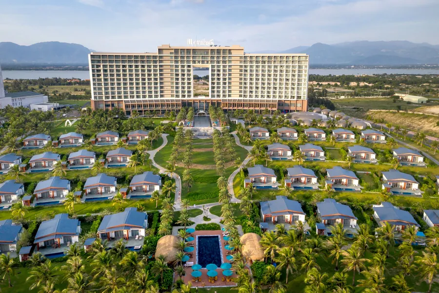Aerial view of resort bungalows among palms and mountains in Cam Ranh, Vietnam