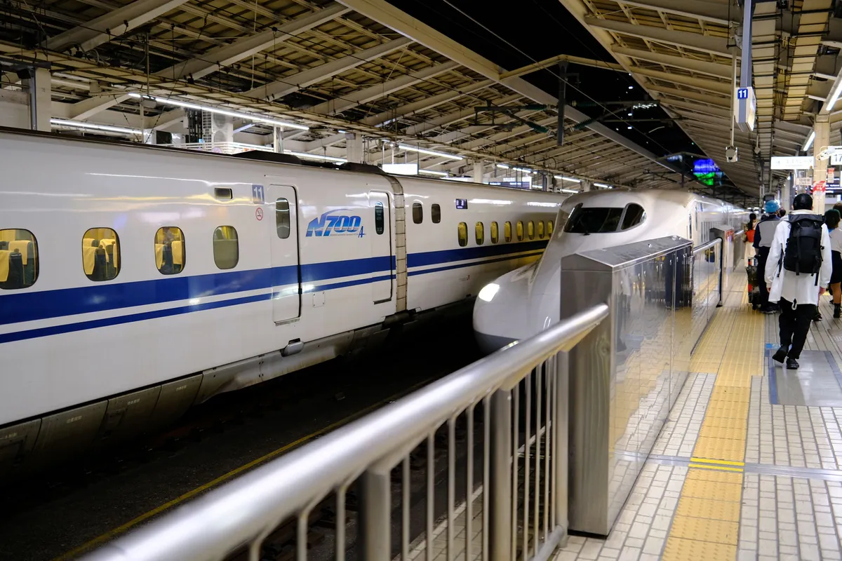 A Shinkansen bullet train at a busy Tokyo station platform with passengers boarding