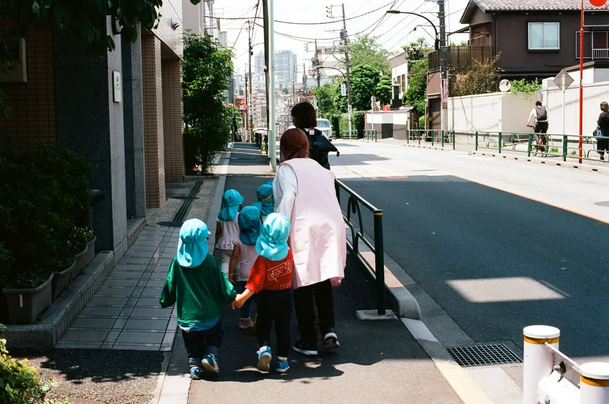 A group of children walking with a teacher on a Tokyo street