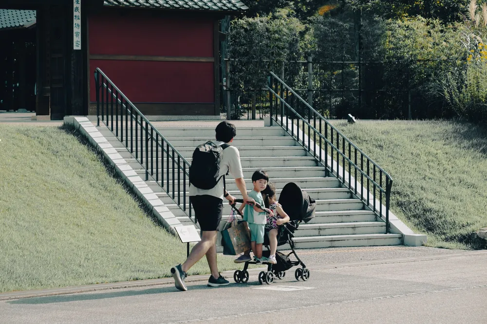 A father pushing a stroller with children on a sunny day in Nagoya, Japan