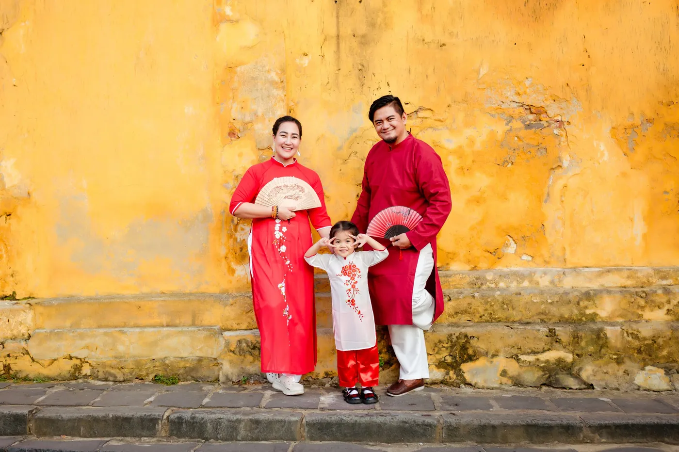 Family wearing traditional ao dai on a historic street in Hội An, Vietnam