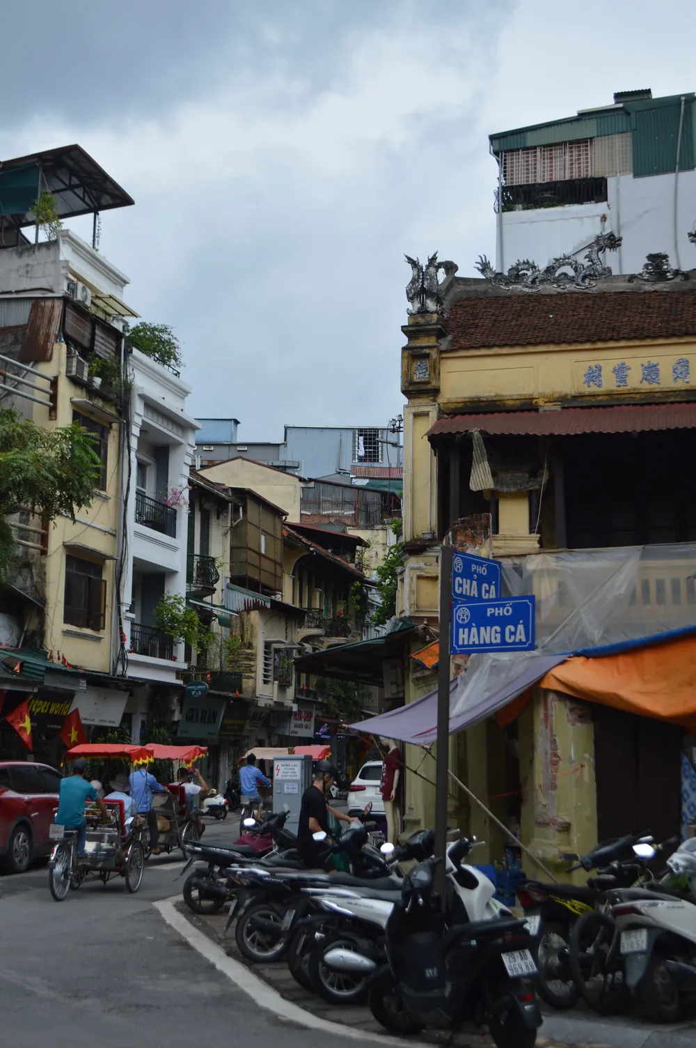 A lively street in Hanoi's Old Quarter filled with scooters and traditional shopfronts