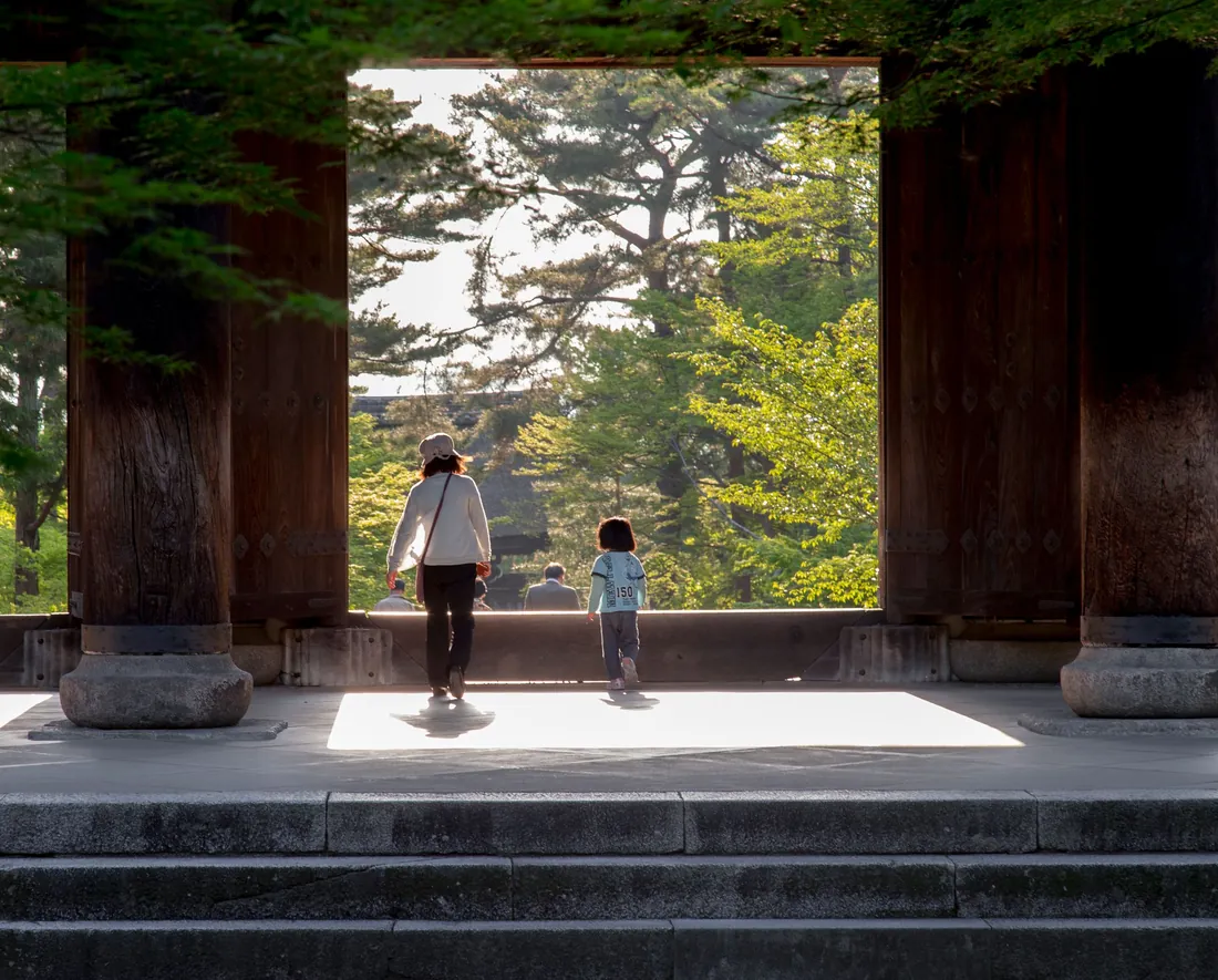 Family walking through a green temple gate in Kyoto, Japan