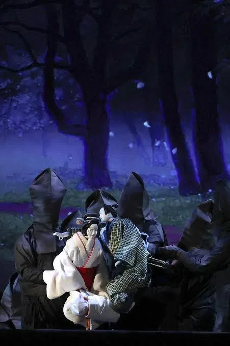 Bunraku puppets worked by puppeteers in black hoods